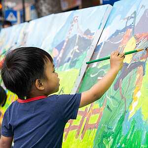 A child painting a on a large canvas. 