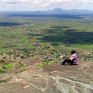 Mann sitzt auf einem Felsvorsprung