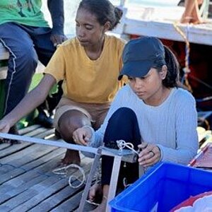 Zwei Frauen sitzen in einem Boot und reparieren es. 