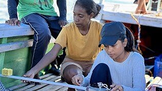 Zwei Frauen sitzen in einem Boot und reparieren es. 