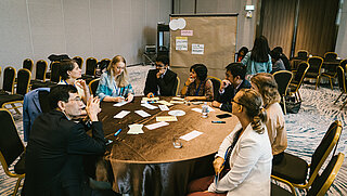 People sit at a group work table for a workshop