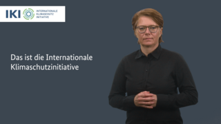 Intro-Bild für das Gebärdenvideo zur IKI. Neben der Gebärdendolmetscherin steht der Titel des Videos "Das ist die Internationale Klimaschutzinitiative".