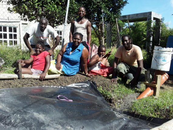 Happy family sitting next to their biogas digester